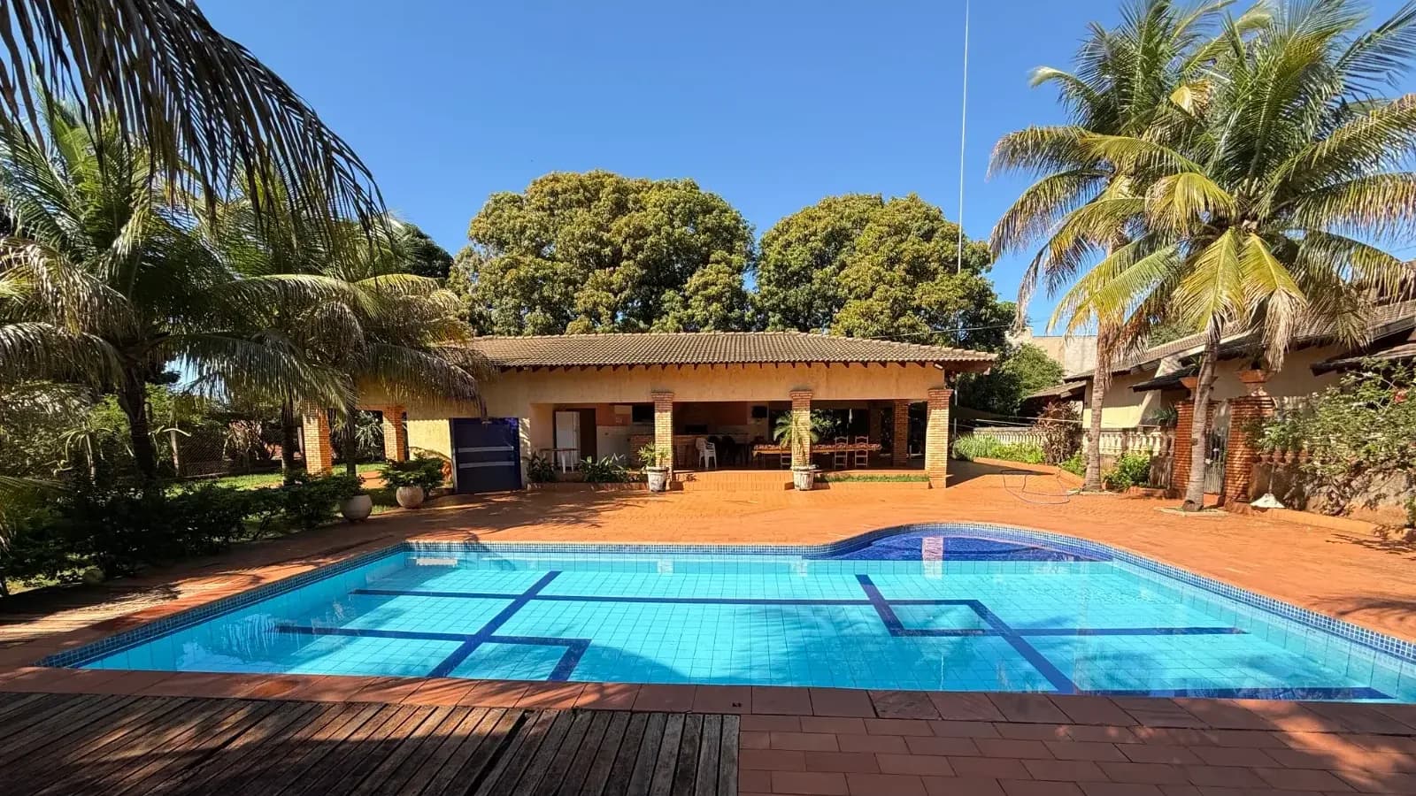 Área de piscina de rancho de temporada com deque de madeira e varanda