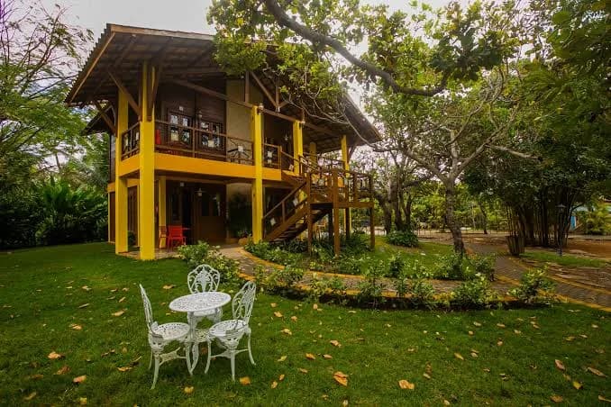 Rancho de dois andares com varanda de madeira e jardim, exemplo de imóvel para alugar em grupo